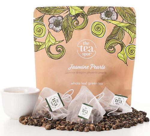 jasmine pearl tea in tea bags and loose leaf tea sits in front of a tan bag reading jasmine pearls 