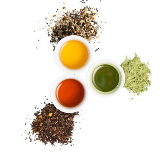 three cups filled with brewed tea with loose leaf tea spilling out on the sides