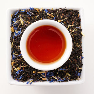a cup of tea sits in a square dish with tea leaves in it