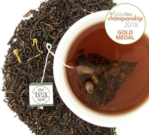 Award-winning Chocolate Black Tea a tea bag is steeping in a mug of tea surrounded by loose leaf tea