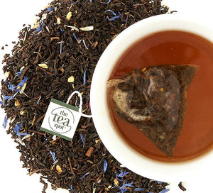 Earl Grey Tea bag Steeped in a mug of tea surrounded by loose leaf tea