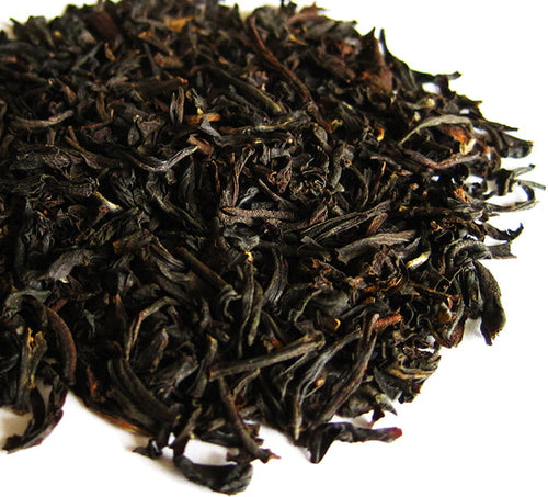 Organic Assam Loose Leaf Tea a pile of black loose leaf tea leaves sits on a white surface