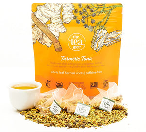 turmeric tonic tea bags sit on a pile of loose leaf tea in front of a bag that reads turmeric tonic a unique blend 
